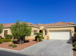 Bella Vita Care Home's single-story front exterior with a two-car garage and desert landscaping.