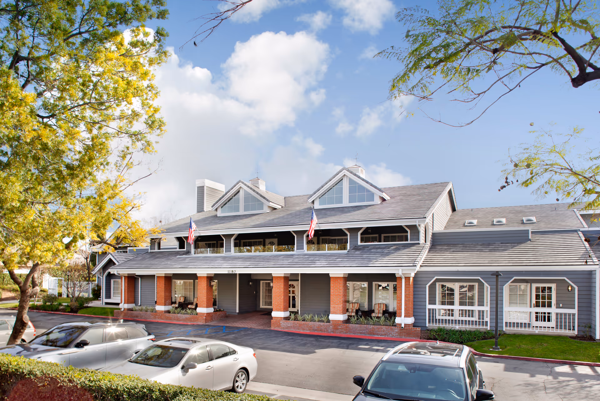 View of Ivy Park at Bradford exterior, a blue-gray building with brick columns and cars.