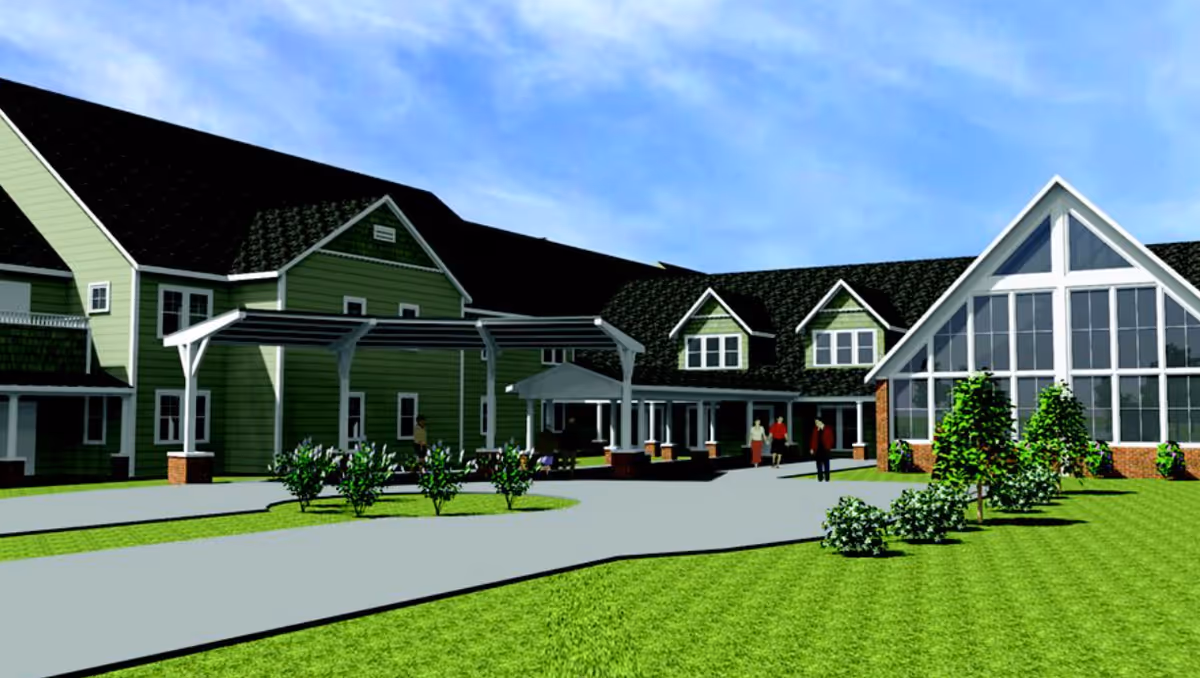 Rendered exterior view of The Village of St. Edward showing the building entrance with a covered drop-off, landscaped lawn, and a large glass-fronted wing.