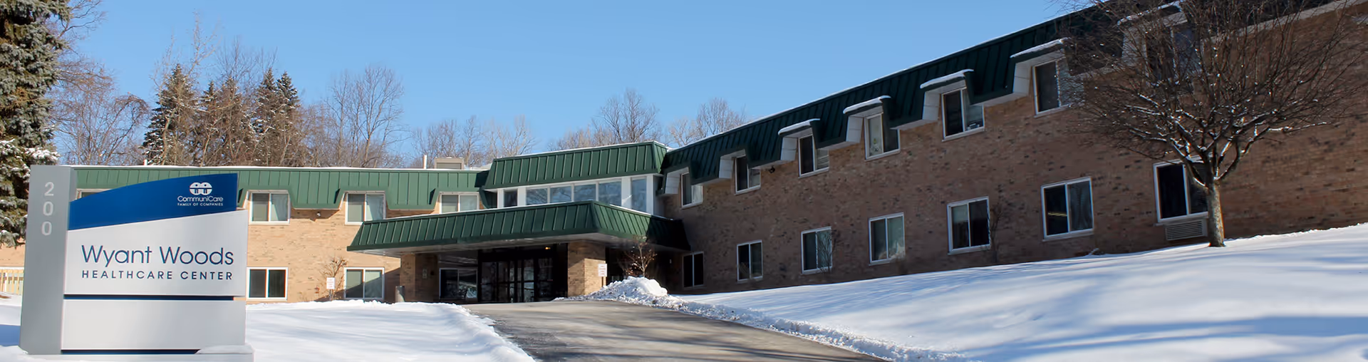 Snow covers the ground outside Wyant Woods Care Center's brick building and entrance sign.