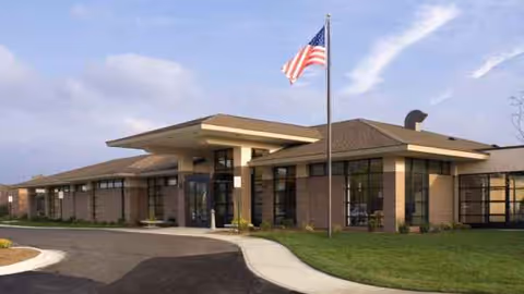 Front exterior of MediLodge of Howell, brick building, entrance, flagpole, and driveway.