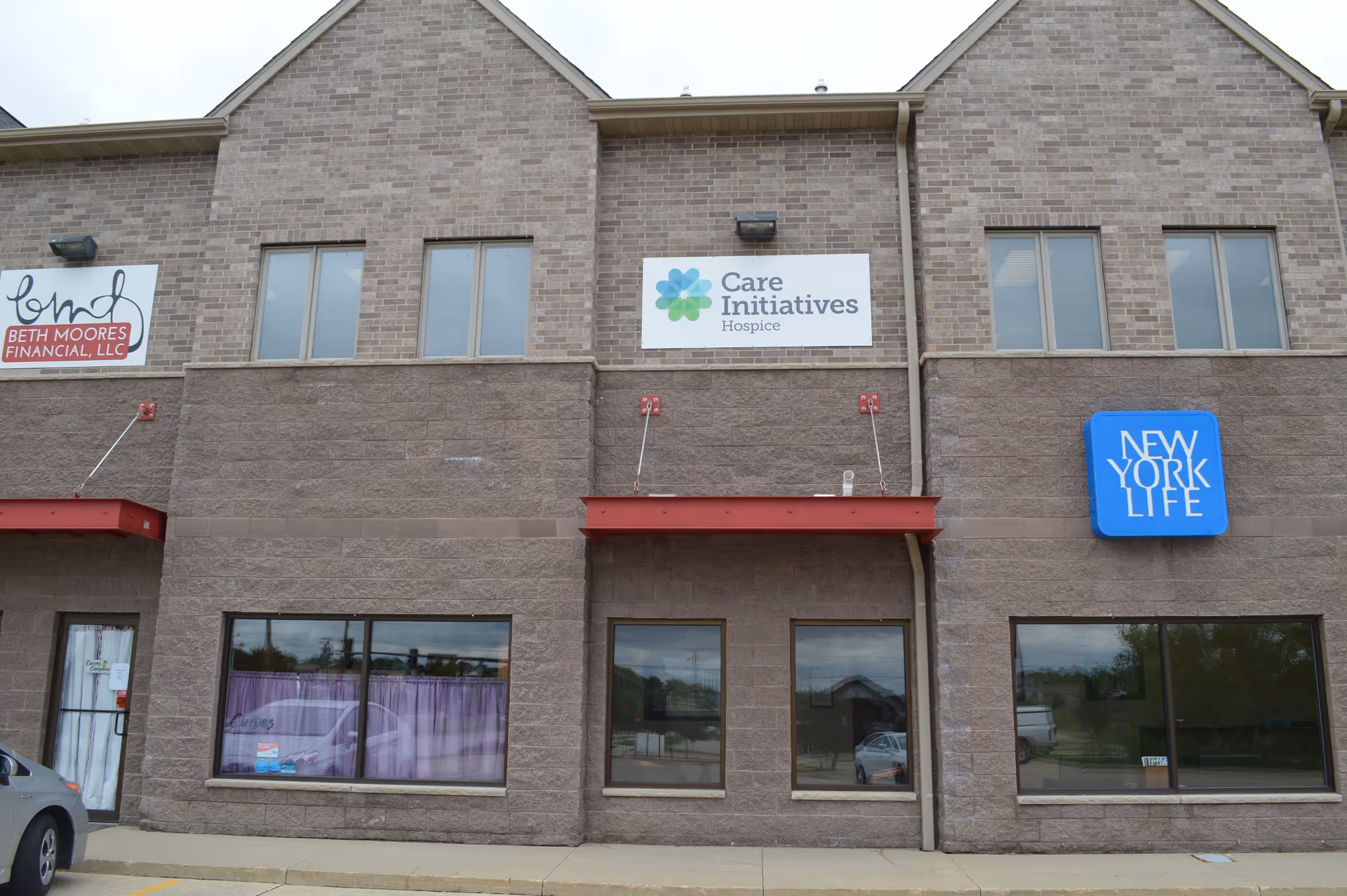Brick building facade with Care Initiatives Hospice sign and New York Life logo.