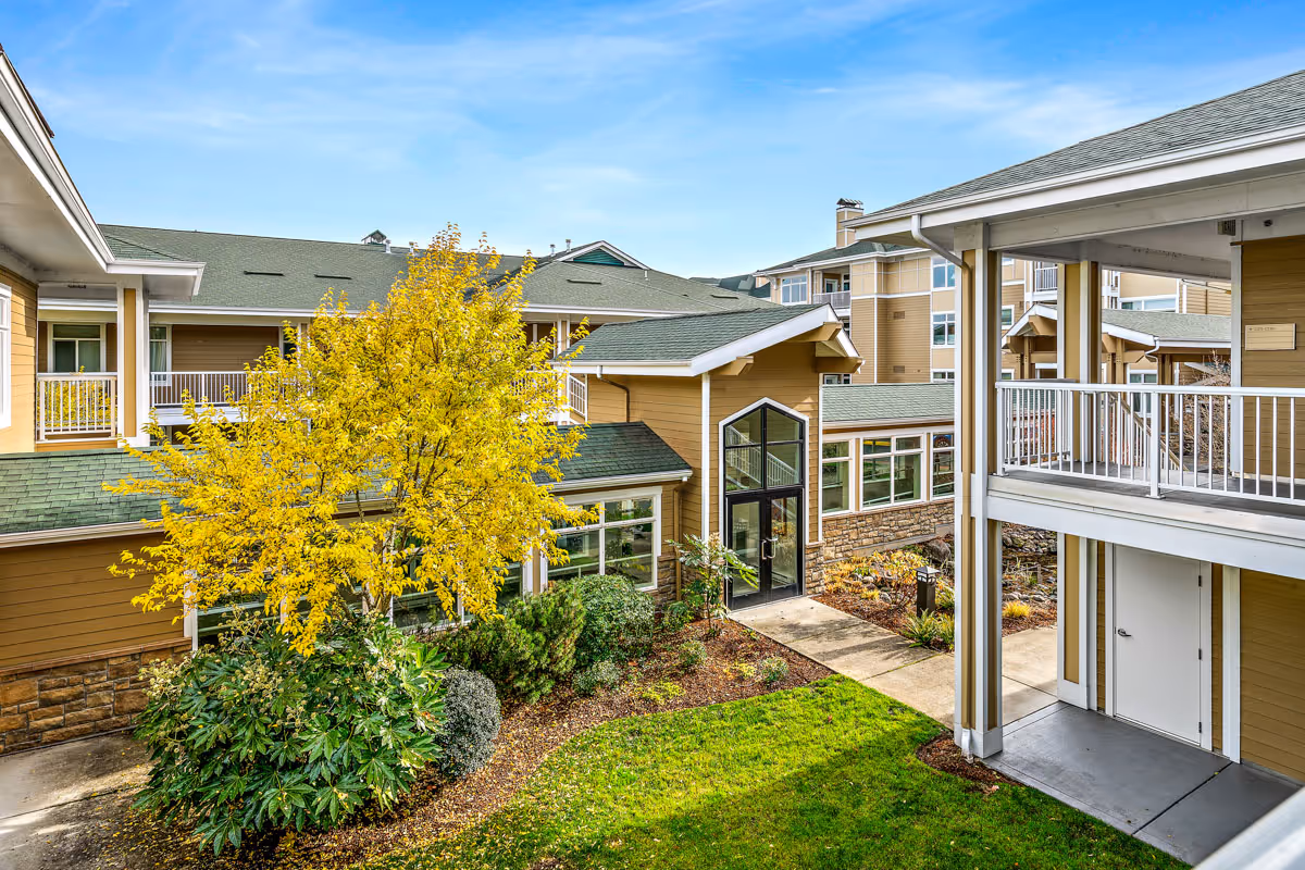 Exterior view of Cascade Manor courtyard with yellow tree and beige buildings.