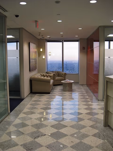 Modern indoor lounge with beige couches and a city-view window.