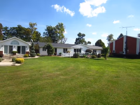 Exterior view of Country Meadows Care Home with a green lawn and white building.