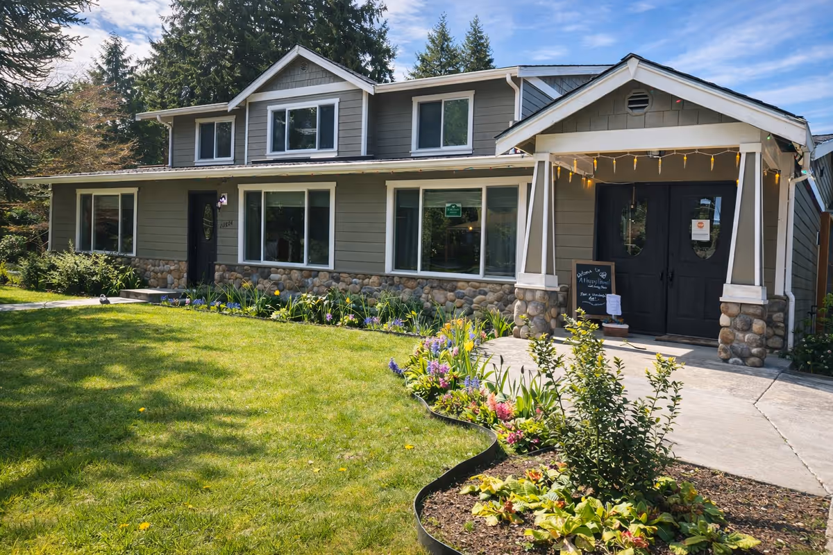 Exterior view of a gray, two-story senior living home with a front garden.