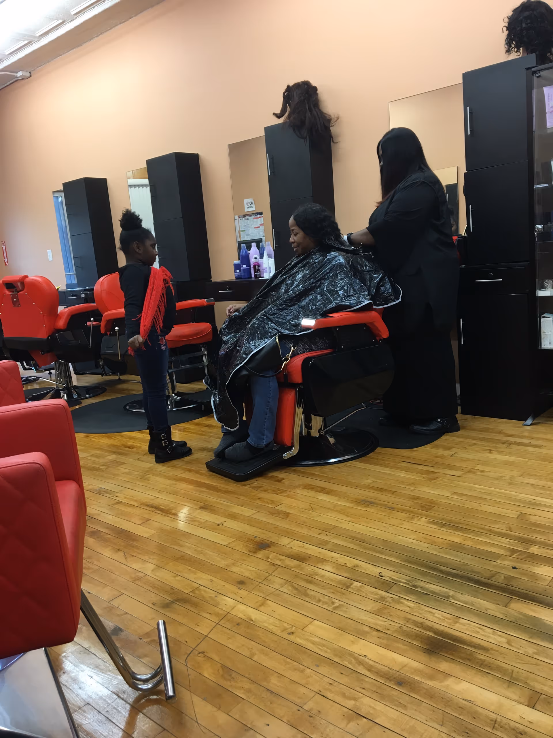 Hair salon inside Heritage at Falmouth with a client in a red barber chair and stylists.