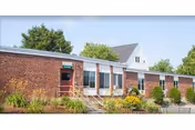 Exterior view of The Elms Center: brick front entrance with landscaping.