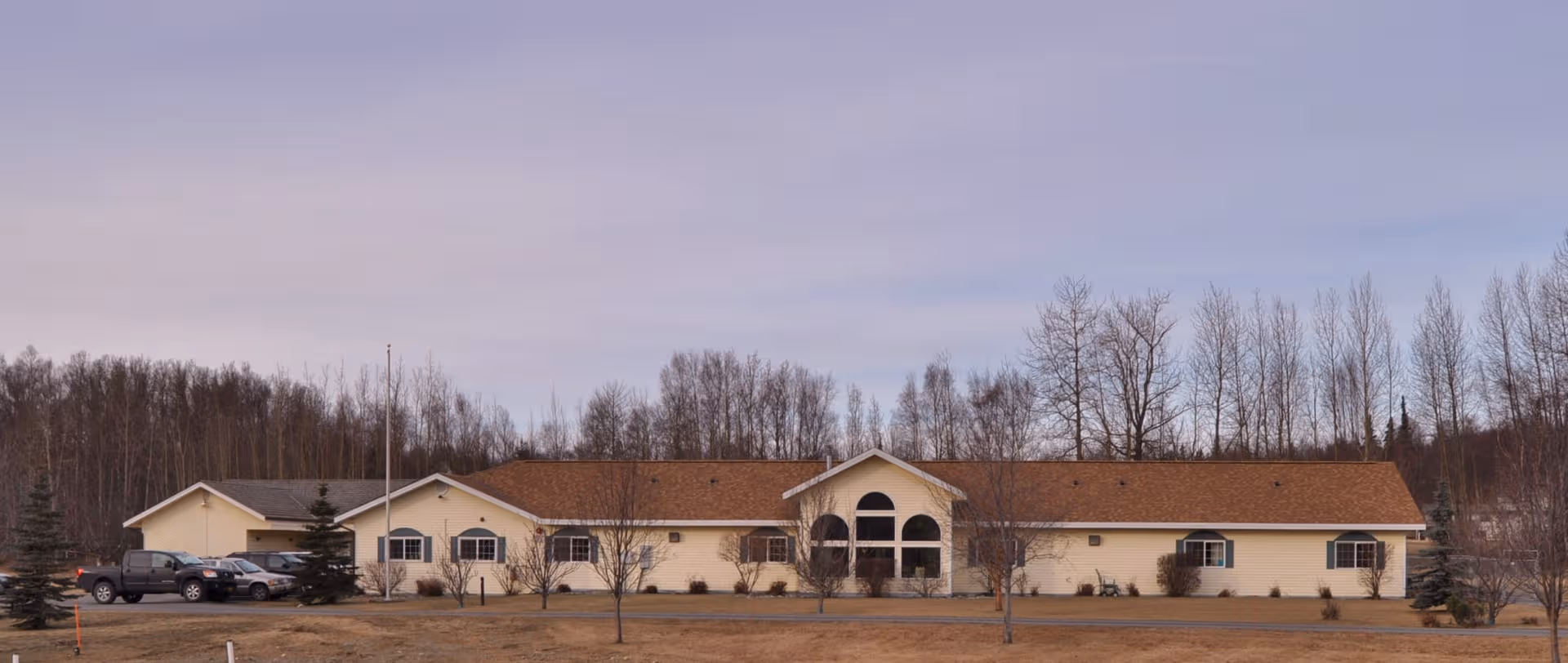 Exterior view of Tranquility Manor Estates, a single-story senior living facility, with parked cars.