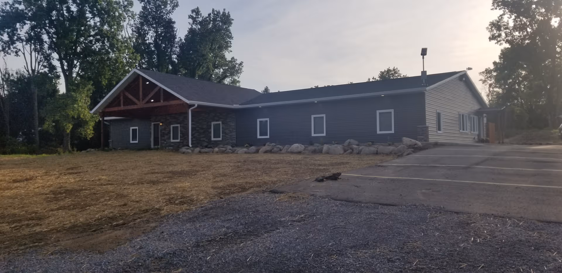 Single-story blue-gray senior living building with stone accents and a parking lot.