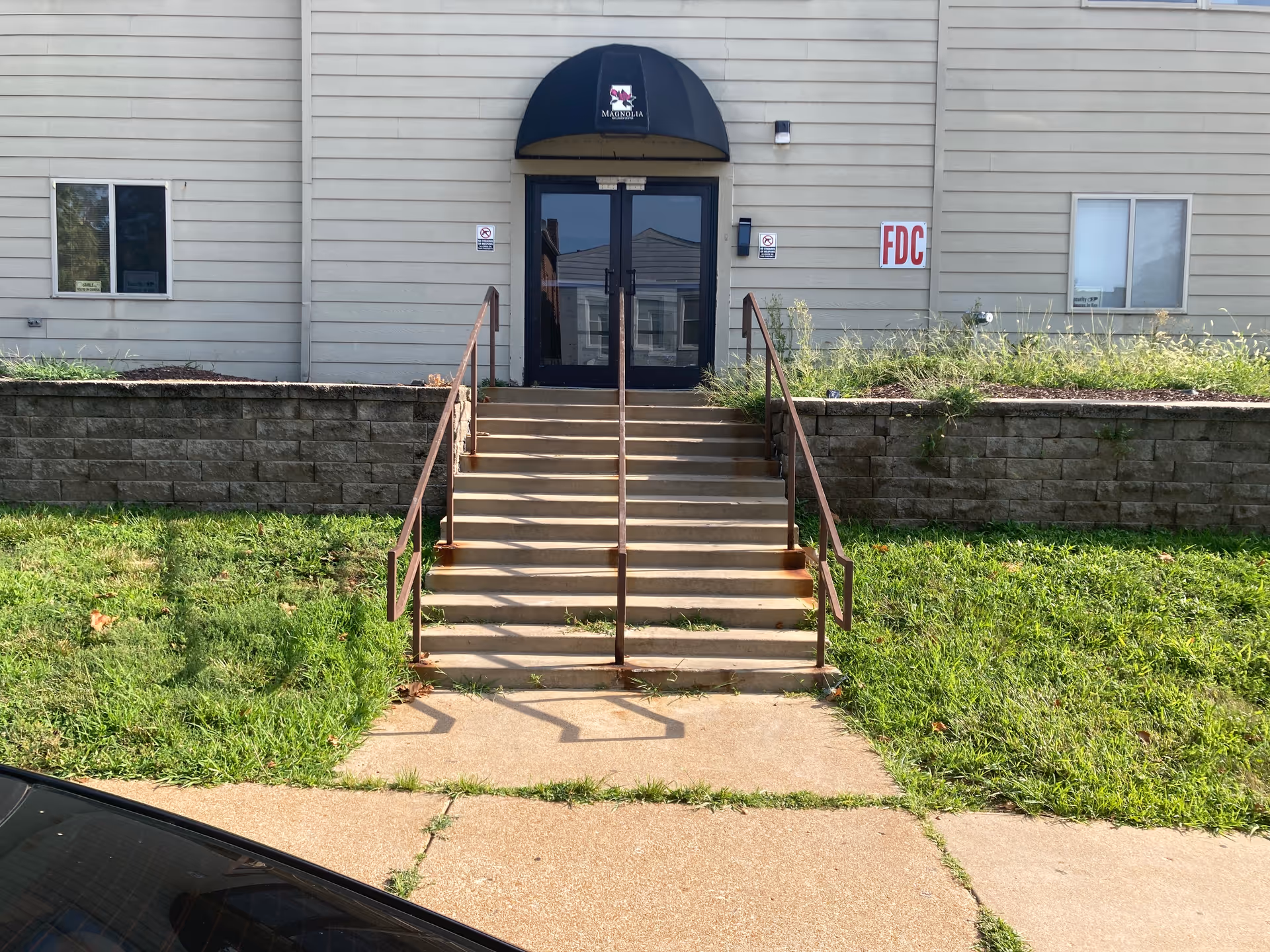 Front entrance of Dutchtown Care Center, stairs, double doors, and landscaping.