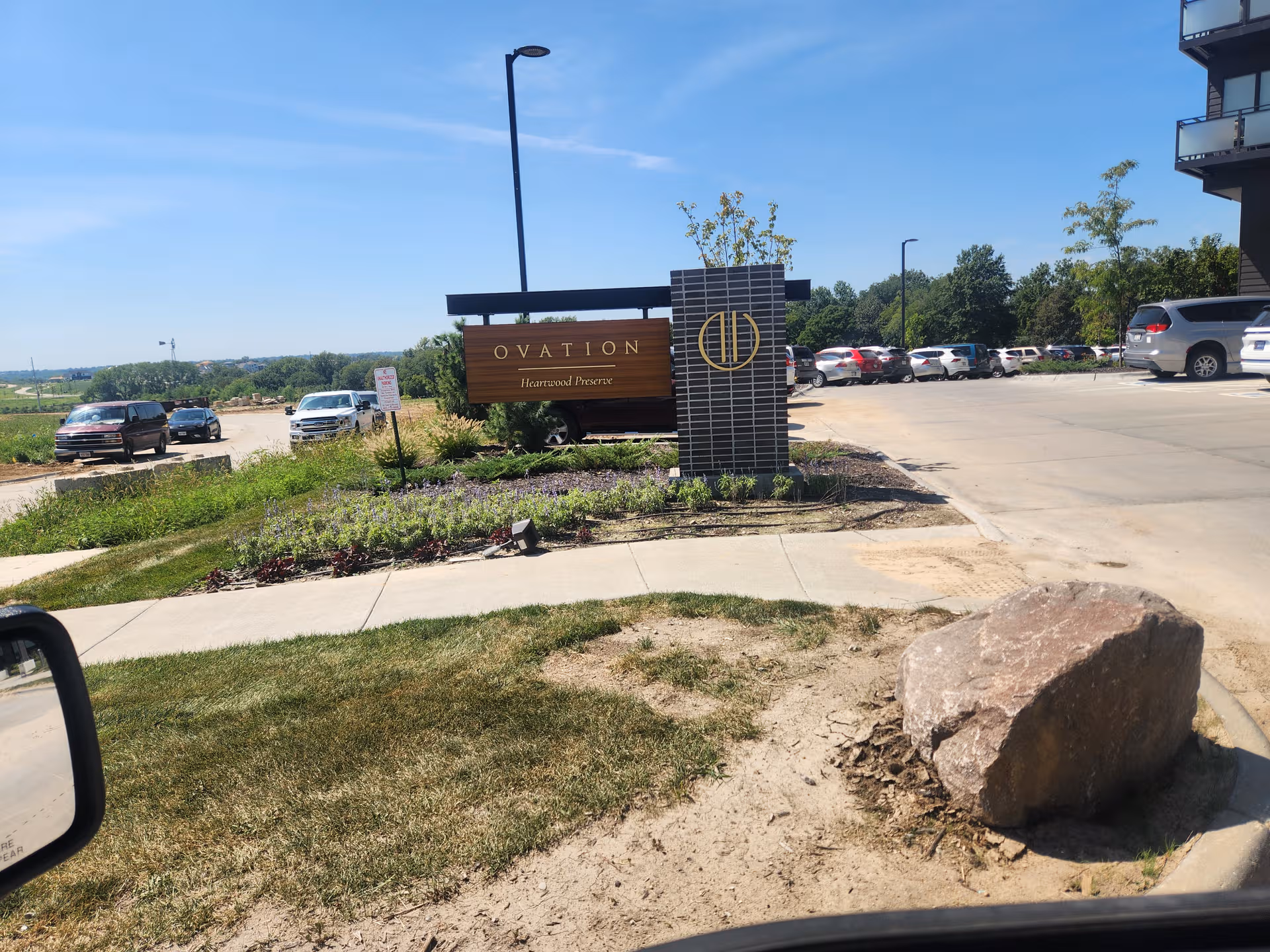 Outdoor view of Ovation Heartwood Preserve entrance sign with parking and landscaping