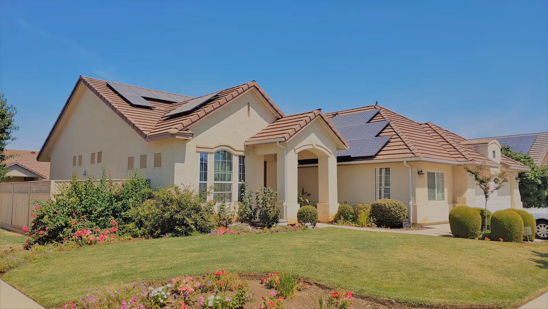 Front exterior of a beige single-story residence with a landscaped lawn and solar panels.