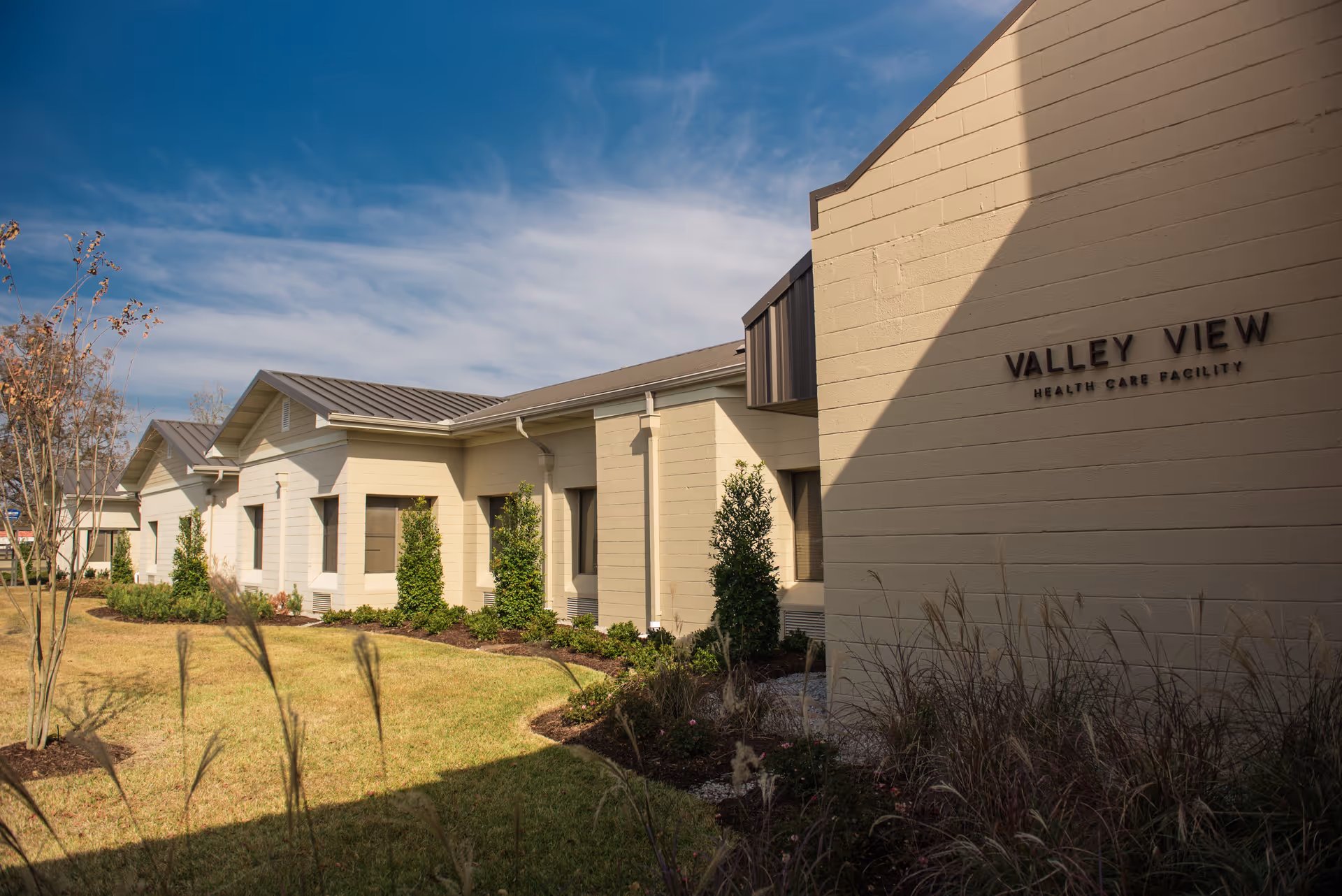 Exterior view of Valley View Health Care Facility building with manicured lawn and clear sky.