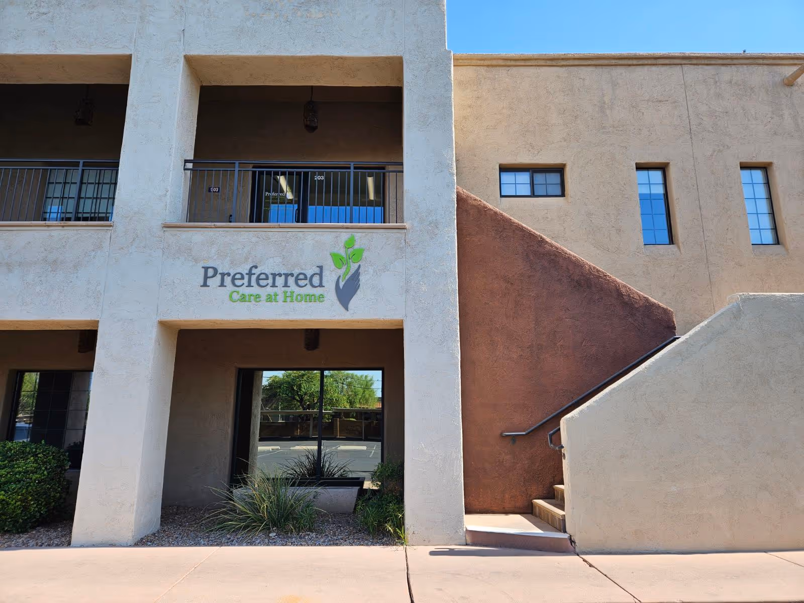 Two-story beige building with 'Preferred Care at Home' sign and glass entrance.