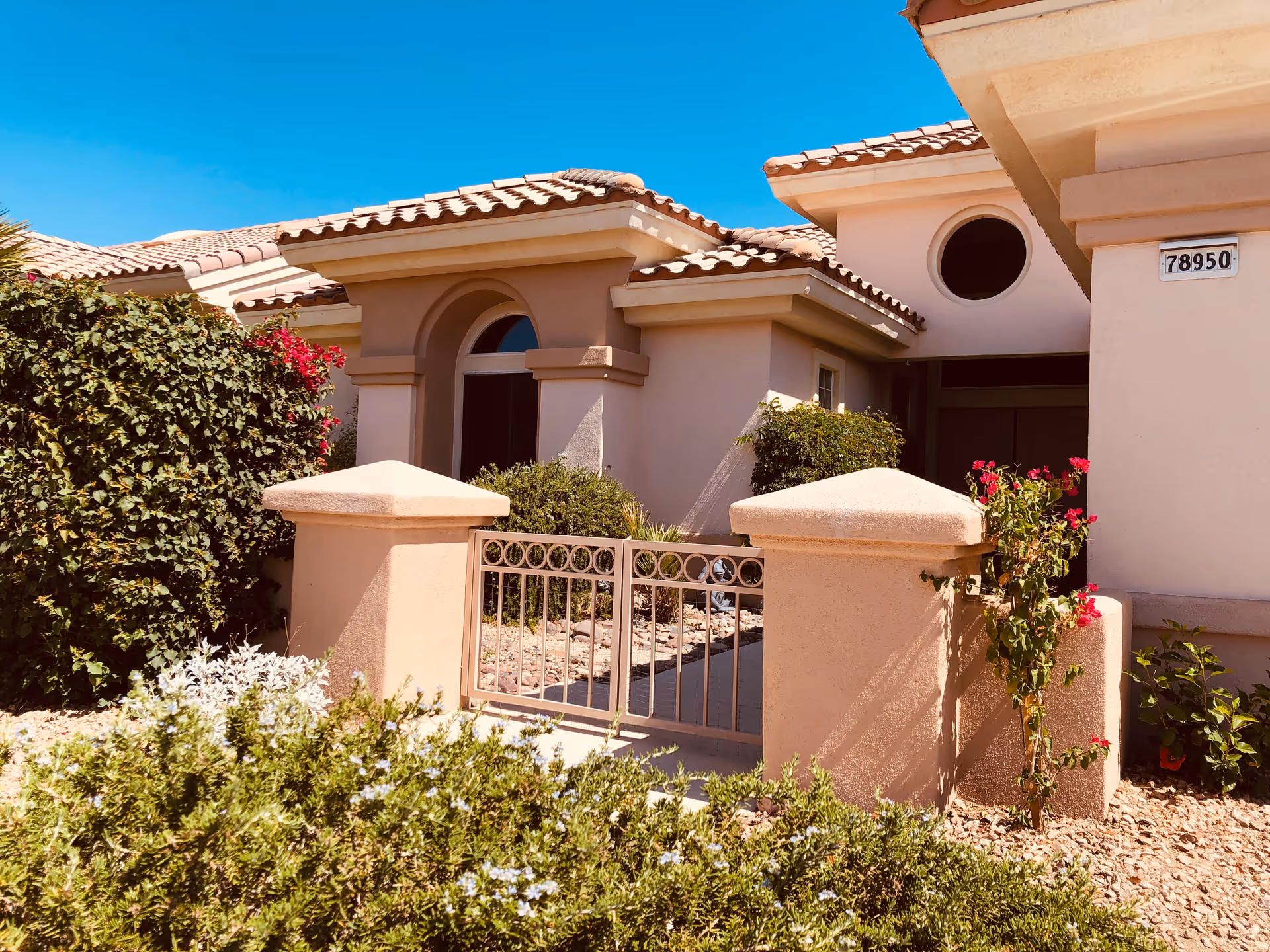 Sun City Villa exterior with a gated entrance, stucco walls, and desert landscaping.