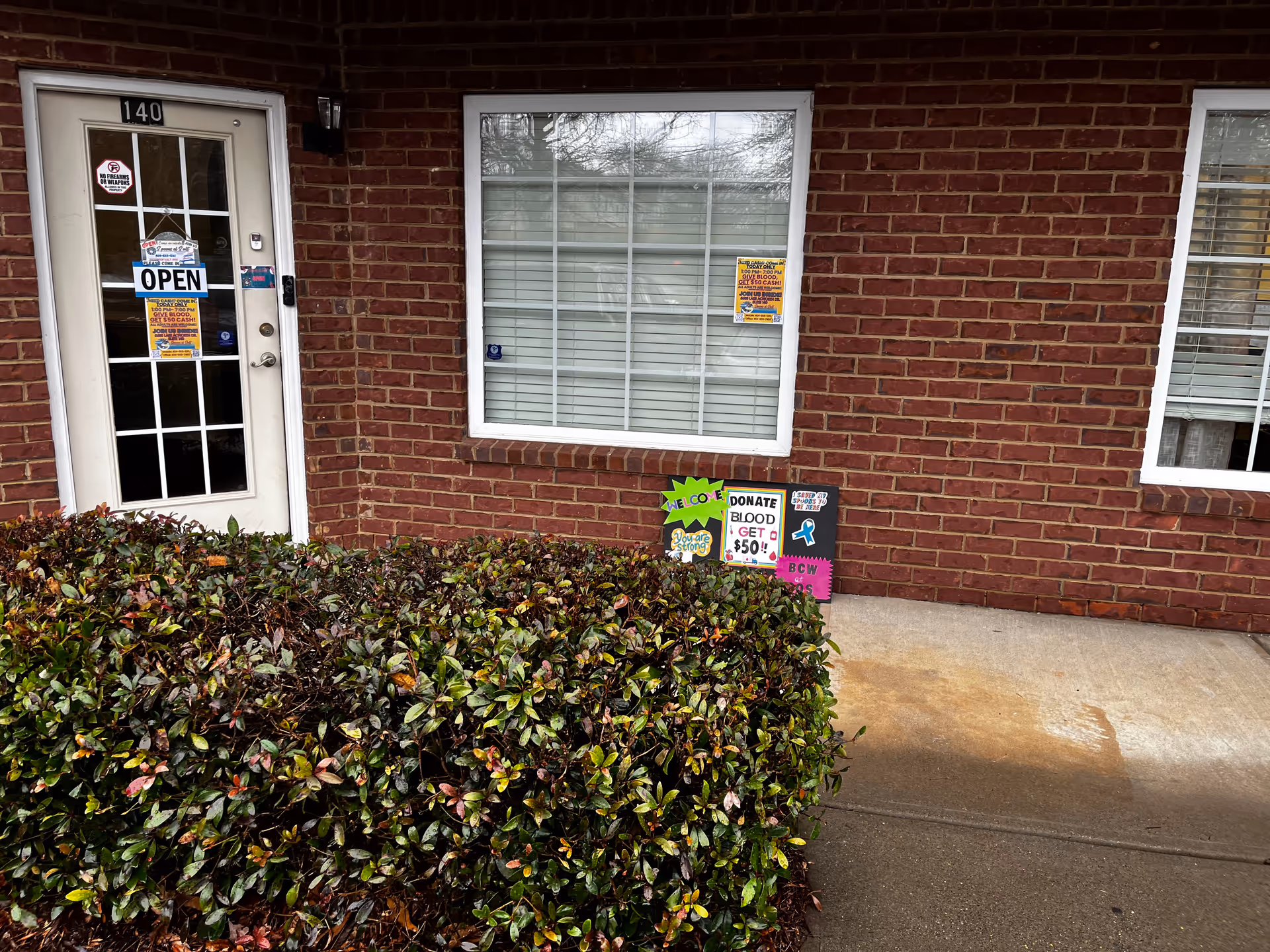 Brick building exterior with a glass door labeled OPEN and a large window.