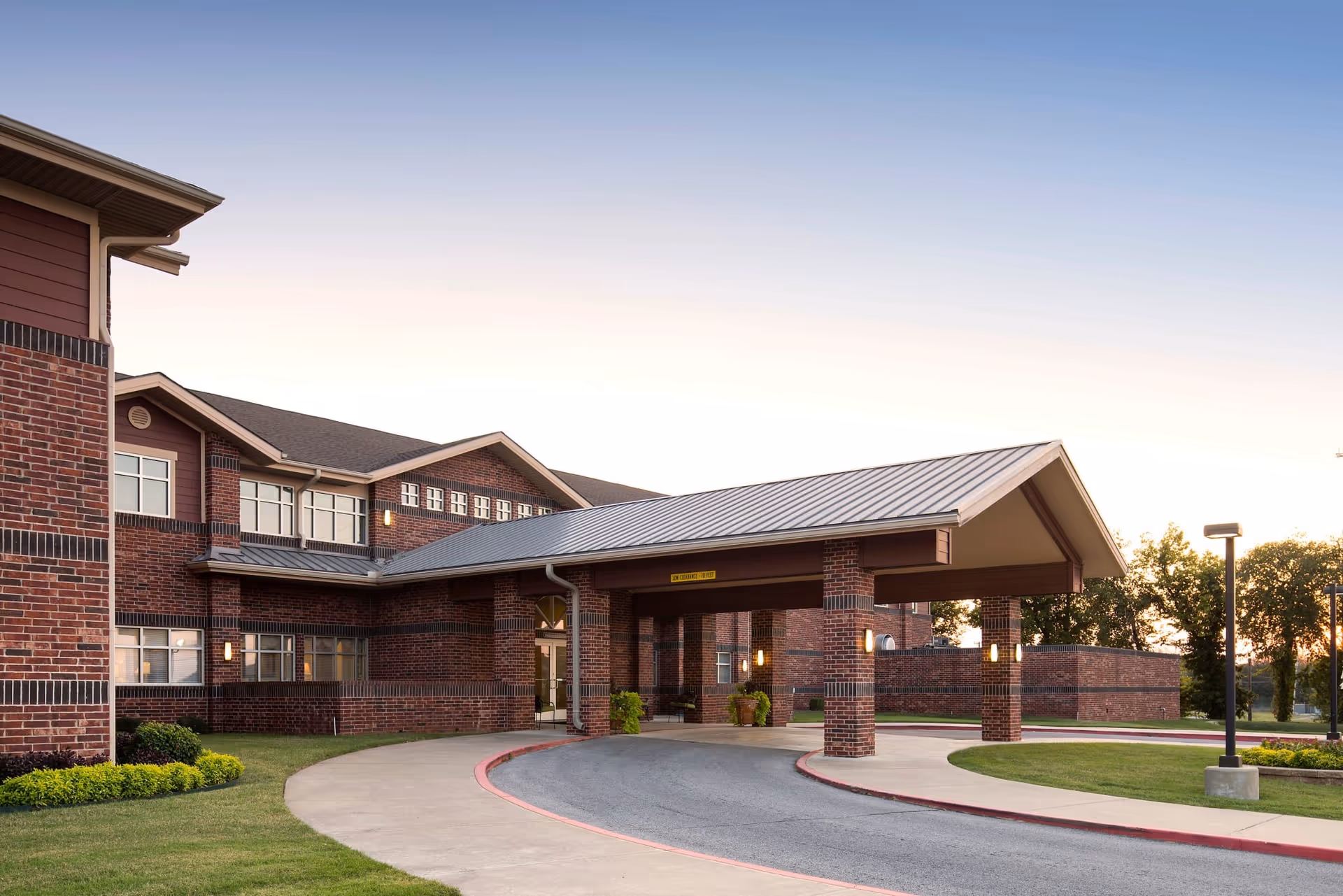 Exterior view of a brick senior living facility with a covered entrance and curved driveway.