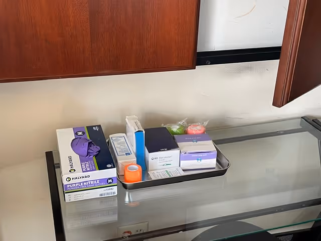 Glass table with medical supply boxes and a tray inside a facility room.