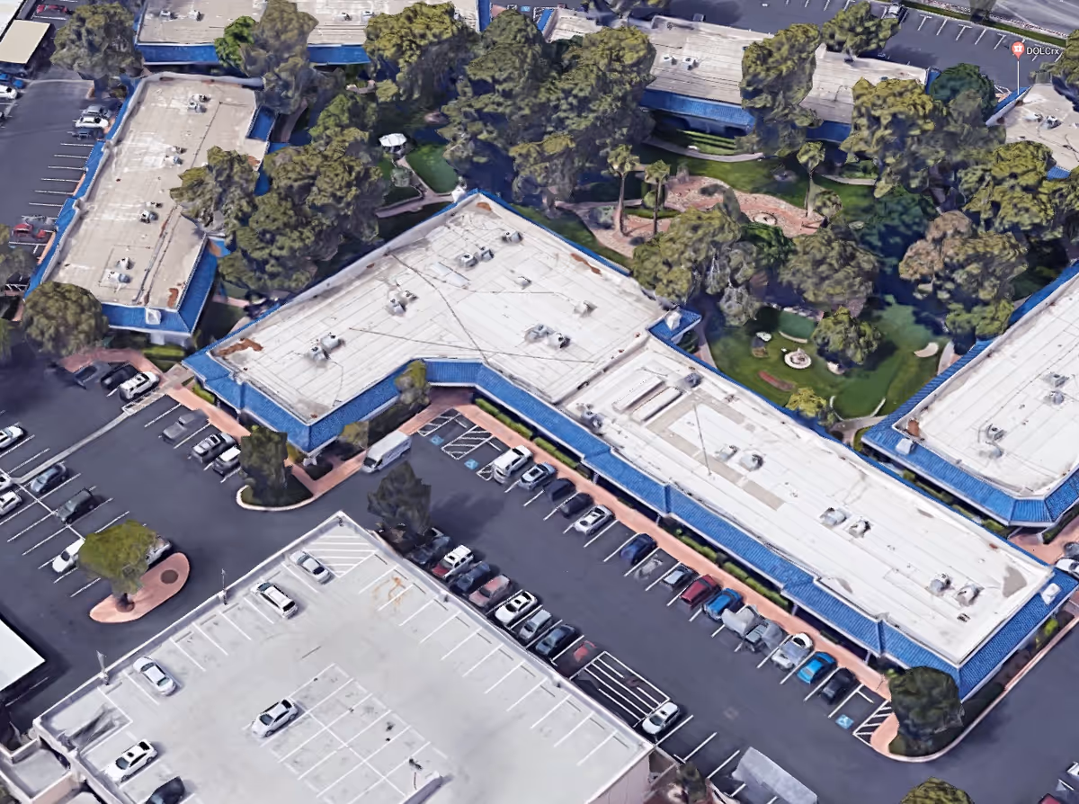 Aerial view of a blue-roofed senior living campus with parking and trees.