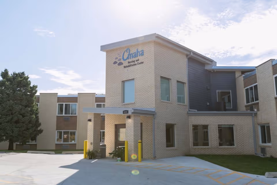 Exterior view of Omaha Nursing and Rehabilitation Center, a beige brick building with a covered entrance.