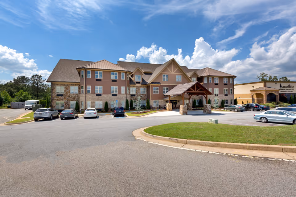 A large senior living facility with stone facade, parking lot, and a covered entryway.