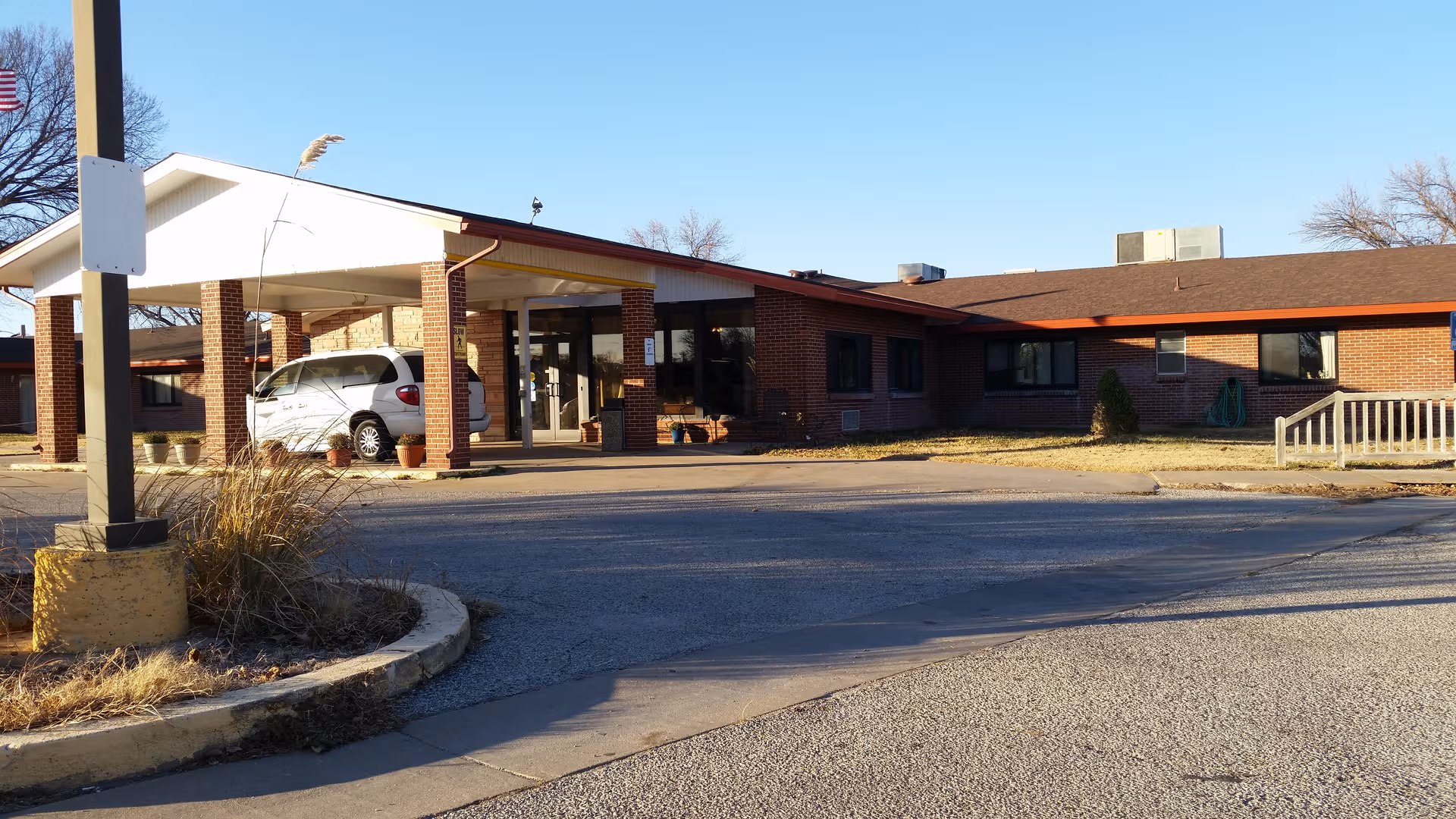 Brick facility with covered entrance and parked minivan under a wide porte-cochère.