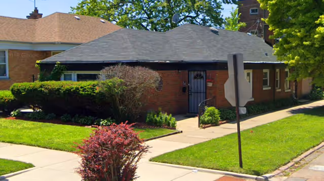 Colfax Manor Assisted Living exterior: brick, single-story building with manicured lawn.