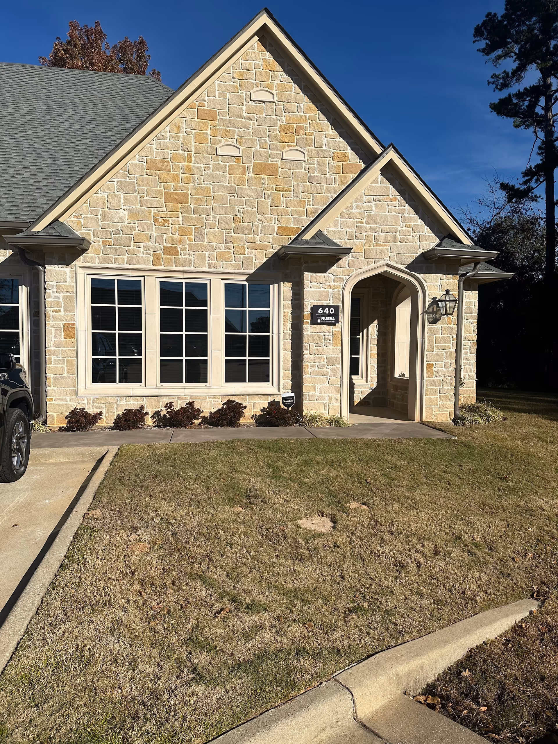 Stone-front building with arched entrance, large windows, and a manicured front lawn.