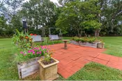 Red brick patio with planters, benches, and a fire pit on a grassy courtyard.