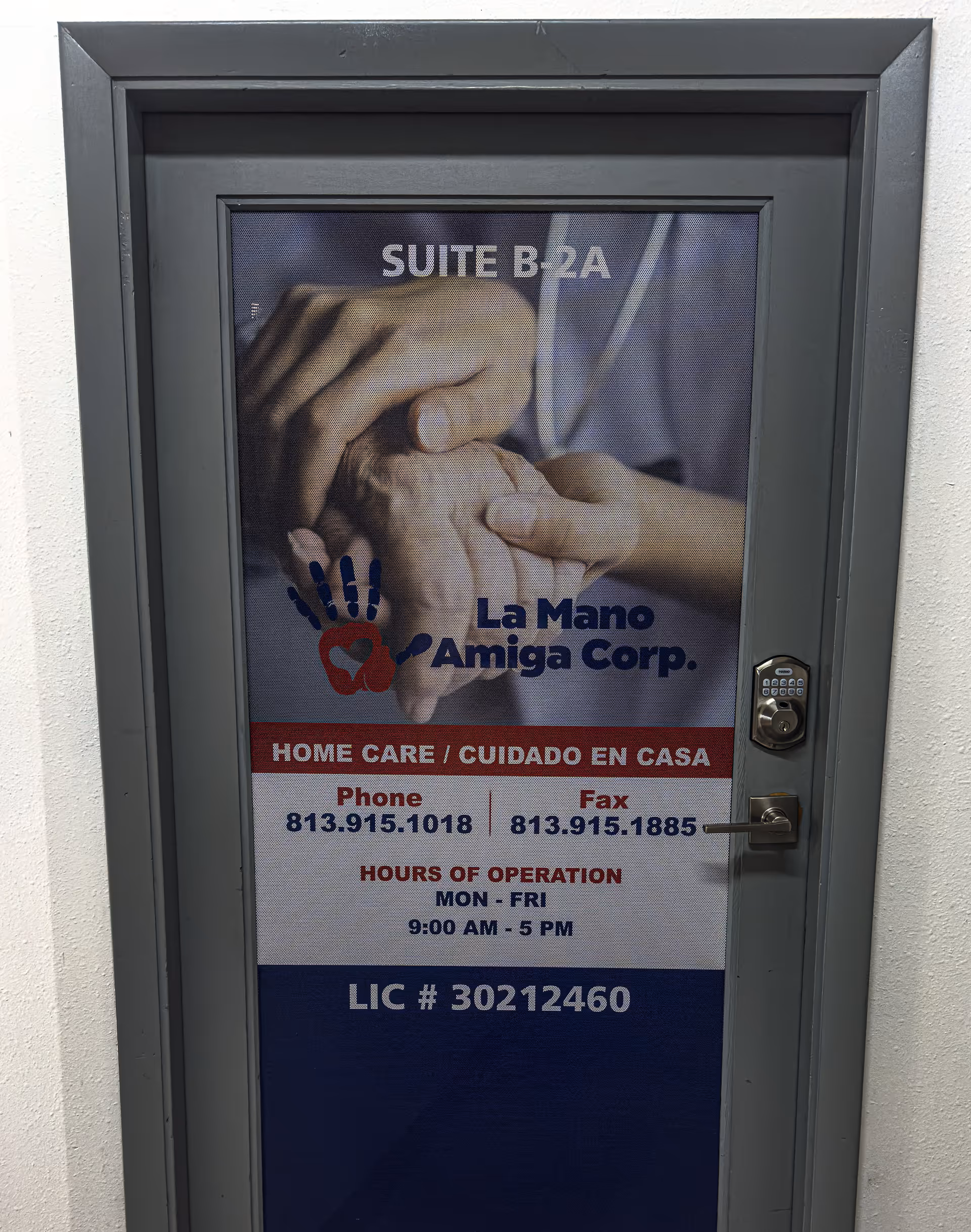 Door with La Mano Amiga, Corp. care signage and contact information in a hallway.