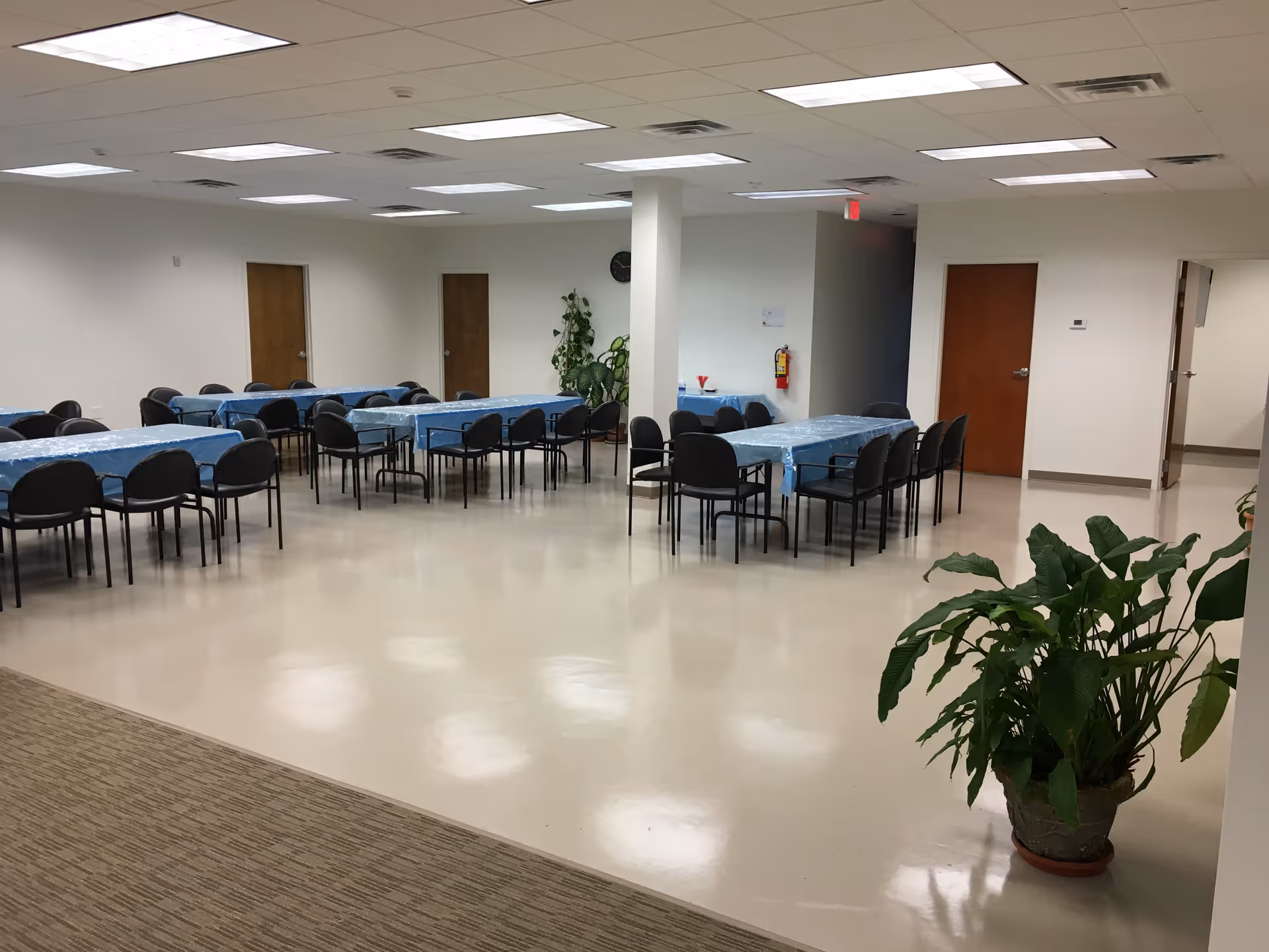 A spacious dining hall with long blue tablecloths and black chairs.