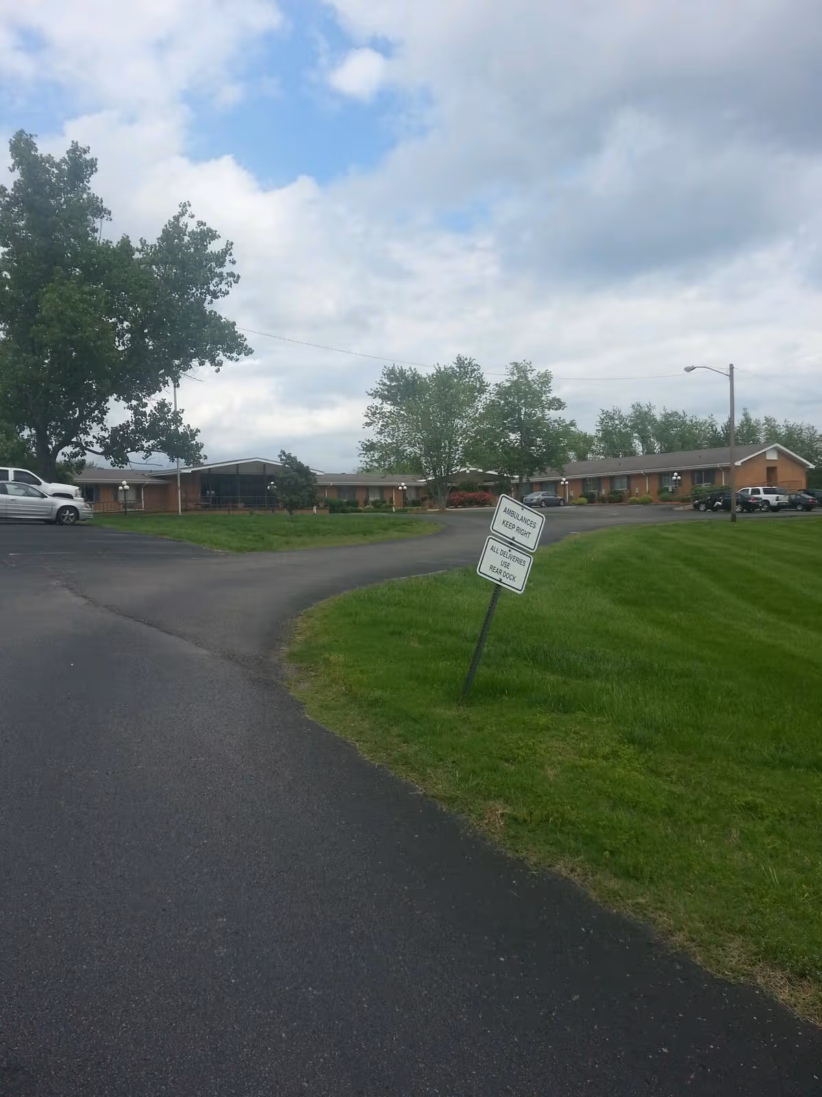 Exterior view of The Waters of Cheatham with driveway, lawn, and parked cars.