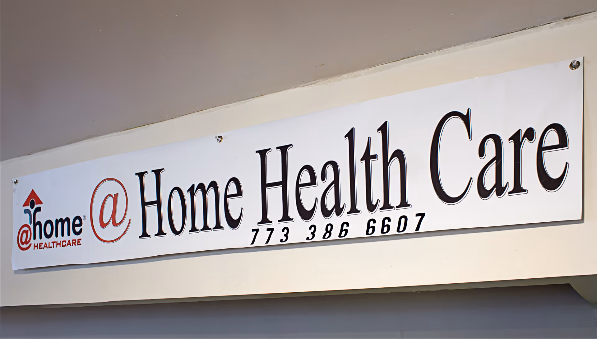 White sign reading '@ Home Health Care' mounted on a building exterior.