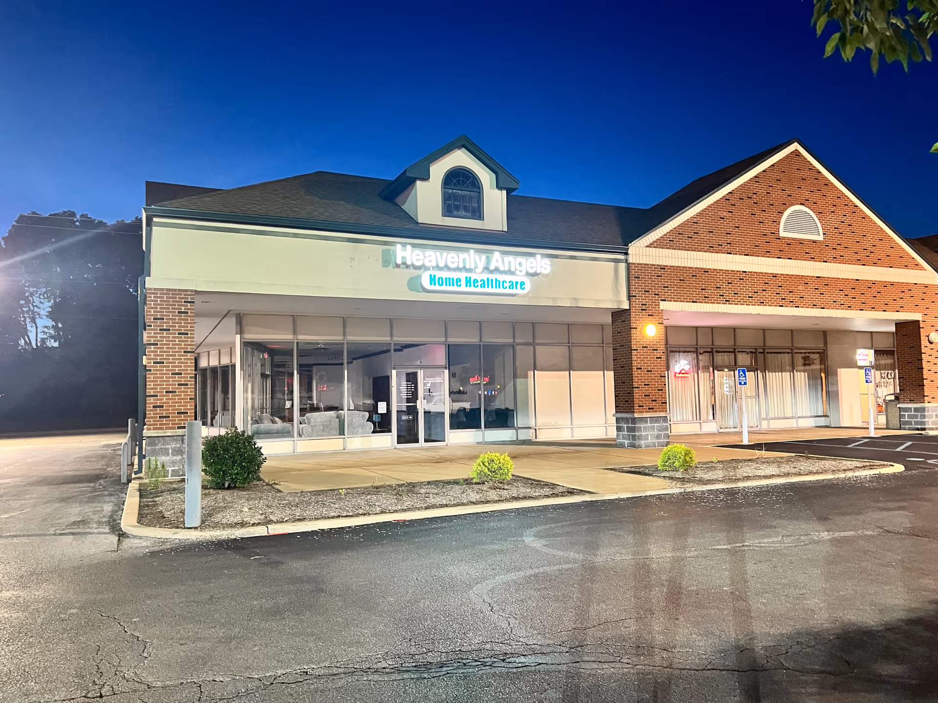 Night exterior of Heavenly Angels Home Healthcare storefront with glass doors and brick facade.