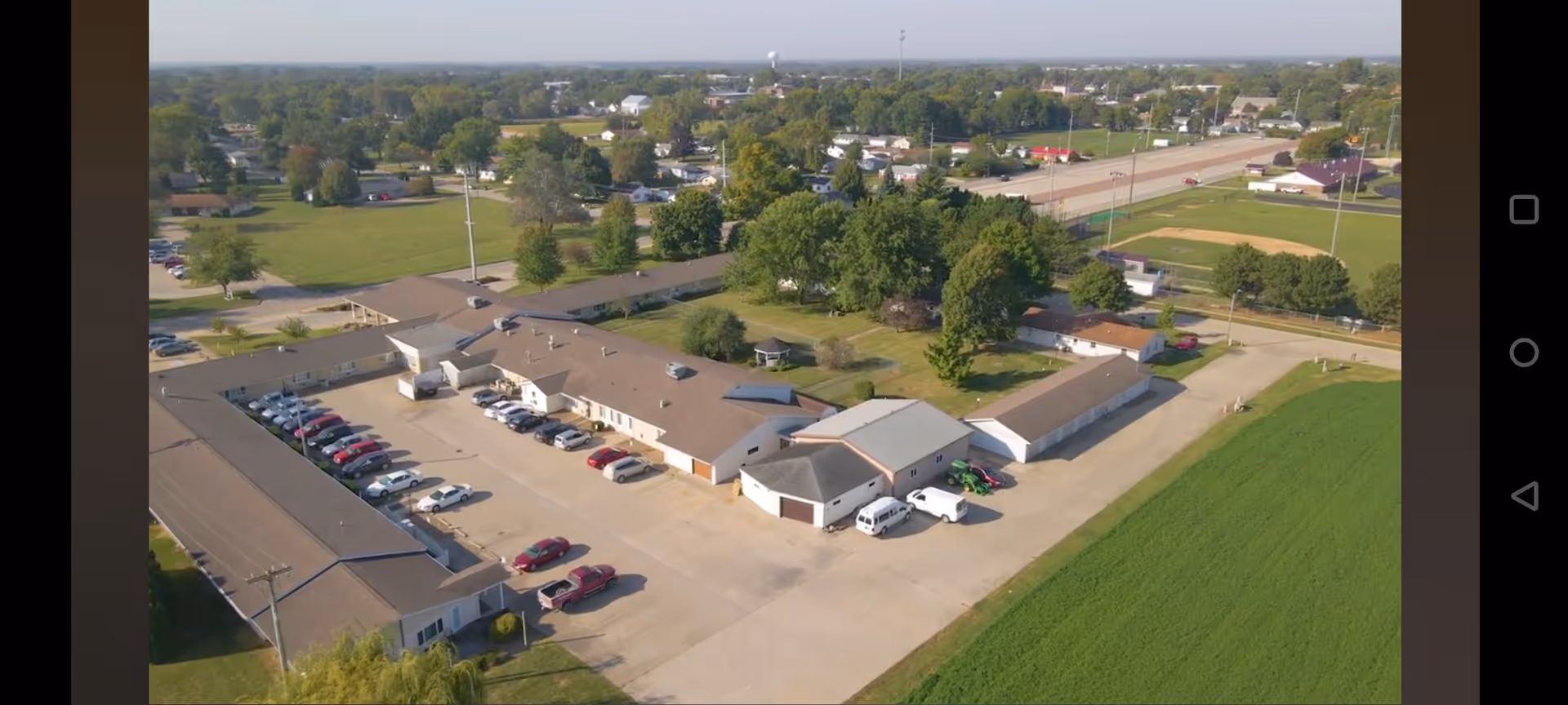 Aerial view of Arbor Court senior living campus with parking lots and surrounding green fields.