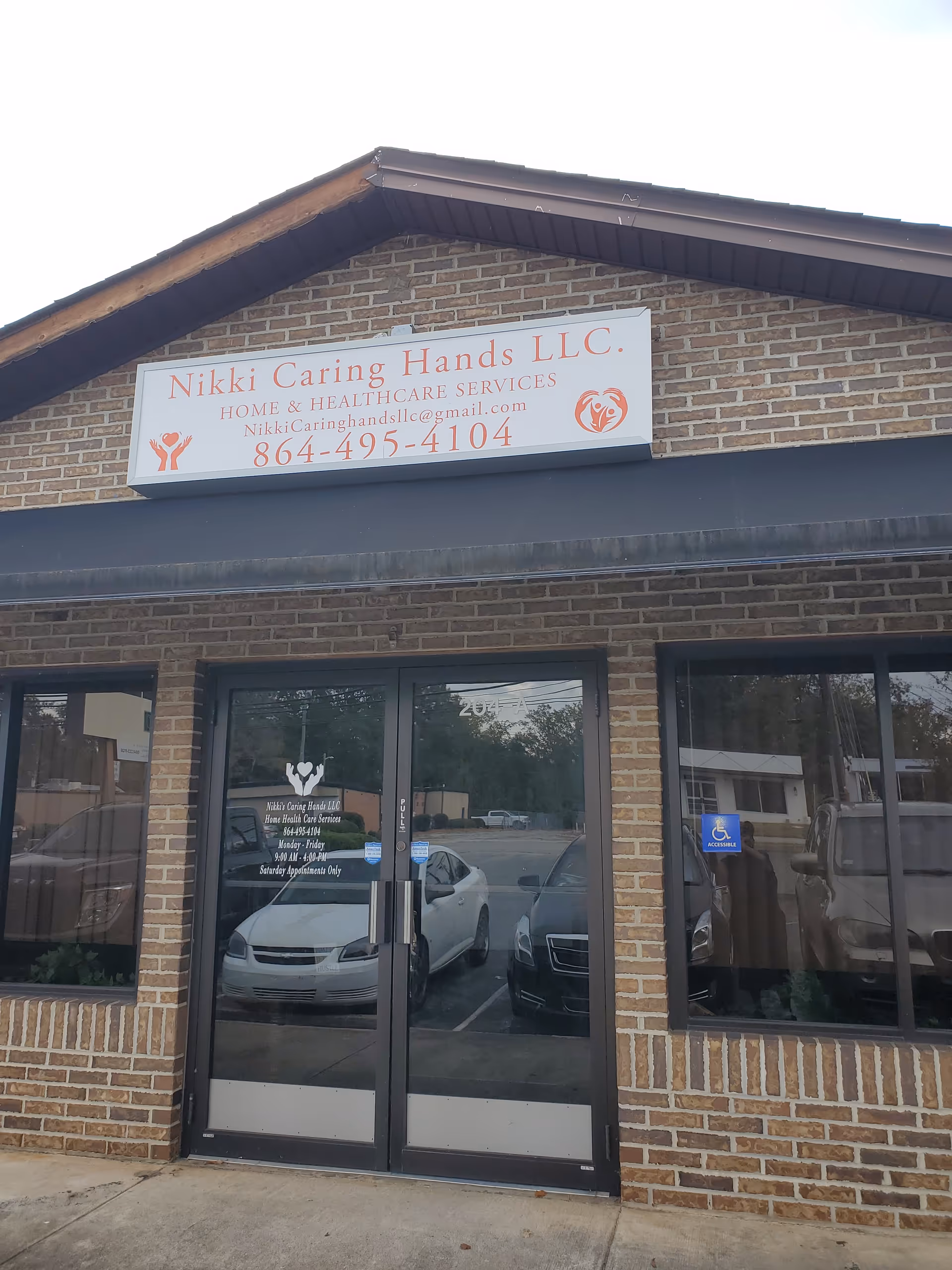 Brick storefront with Nikki Caring Hands LLC sign and glass entrance doors.