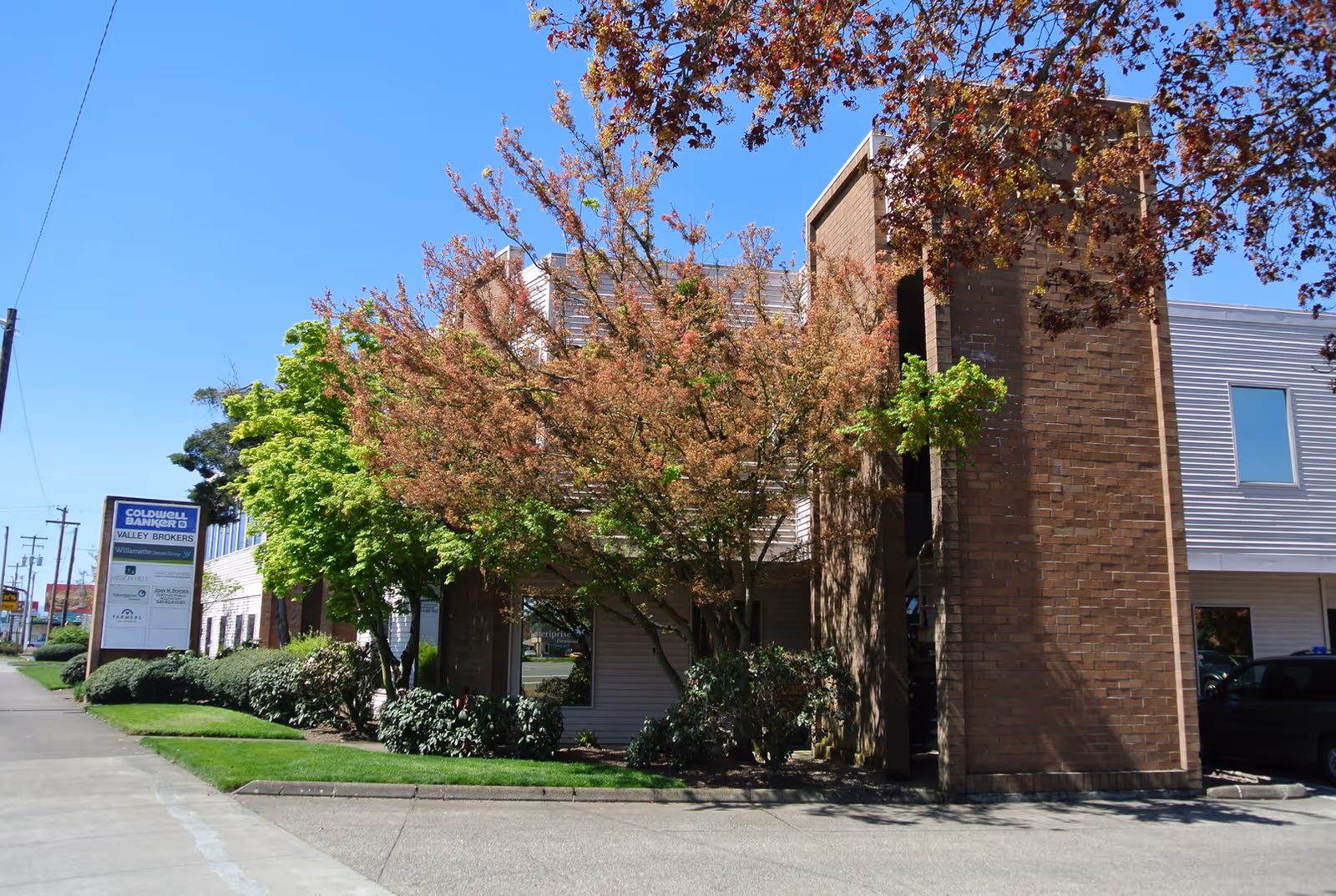 Exterior view of a brick building with trees, sidewalk, and Willamette Valley In-Home Care signage.