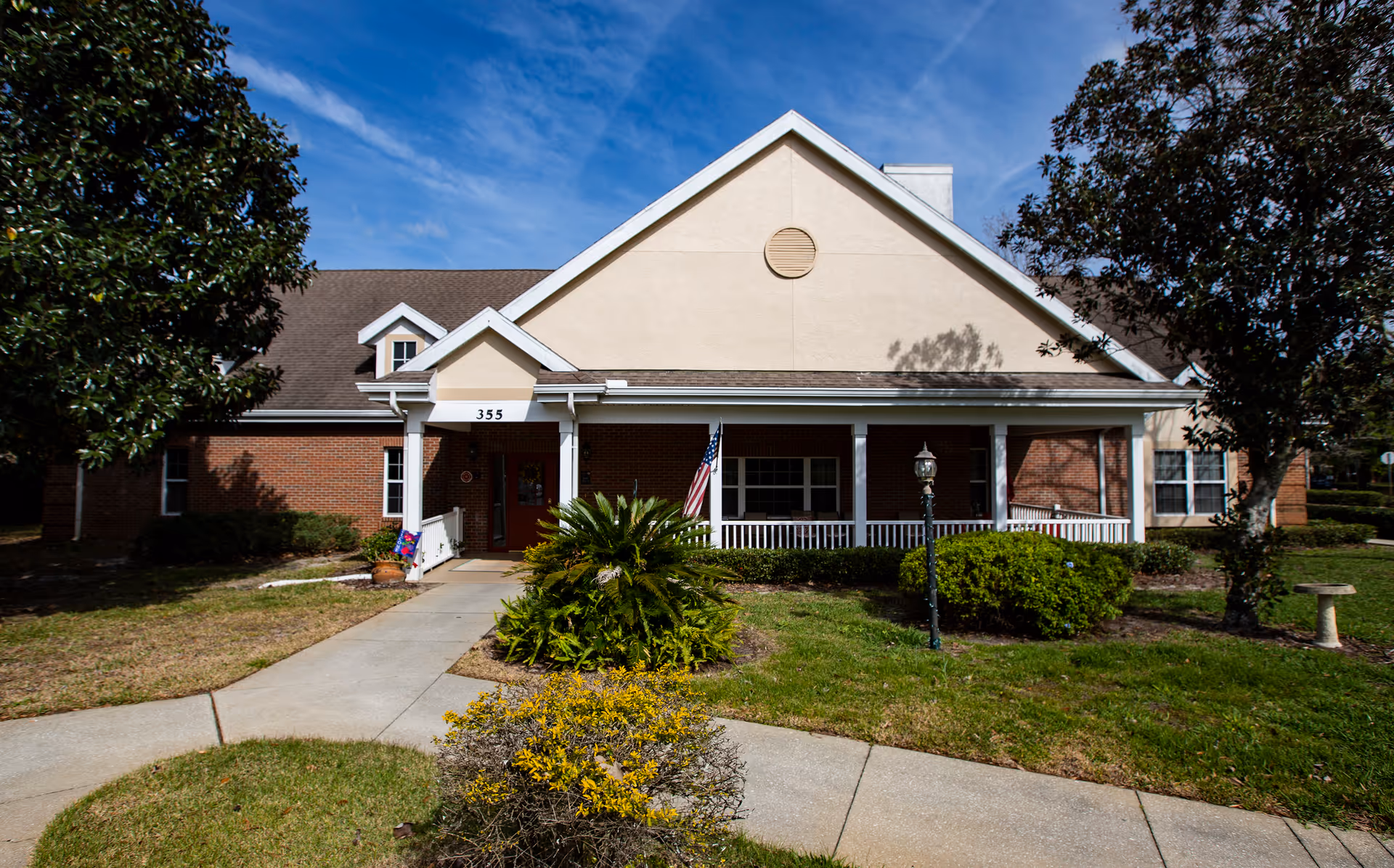 Single-story brick senior living facility exterior with a covered front porch and landscaping.