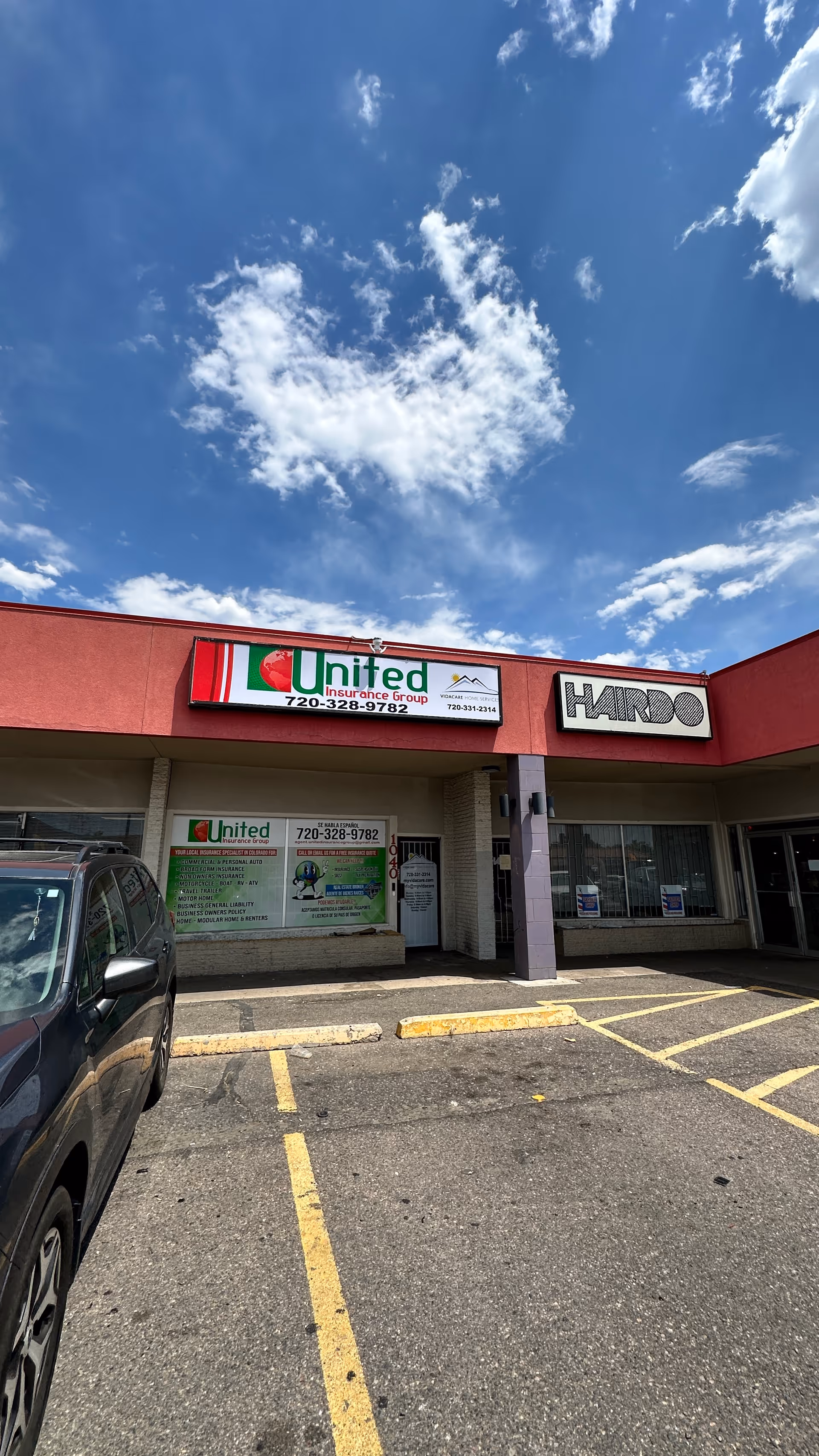 Exterior view of a strip mall storefront with signage and a parking lot.