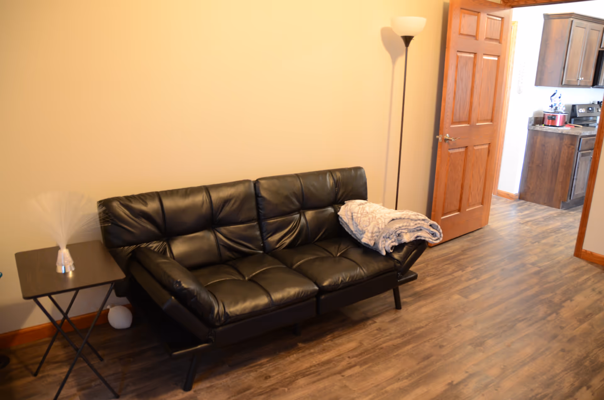 Black leather sofa with a folded blanket in a small living room near the kitchen.