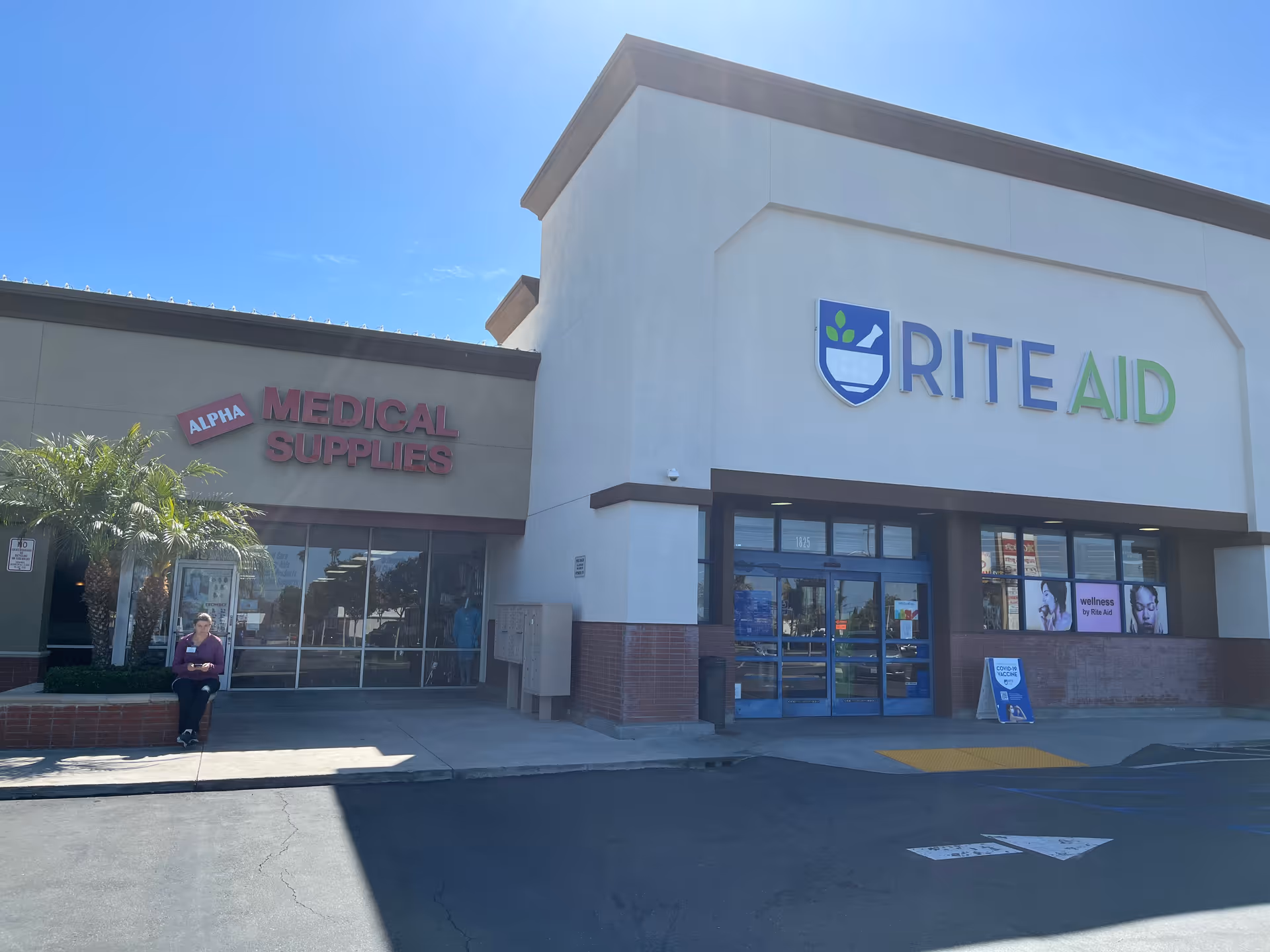 Exterior view of a shopping plaza with Alpha Medical Supplies and Rite Aid storefronts.