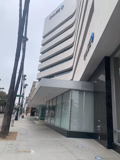 Exterior view of a modern multi-story building with a Chase bank sign along a sidewalk.