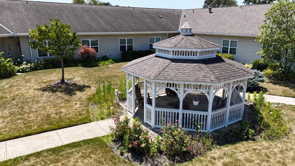 White gazebo in a sunny courtyard with surrounding senior living building