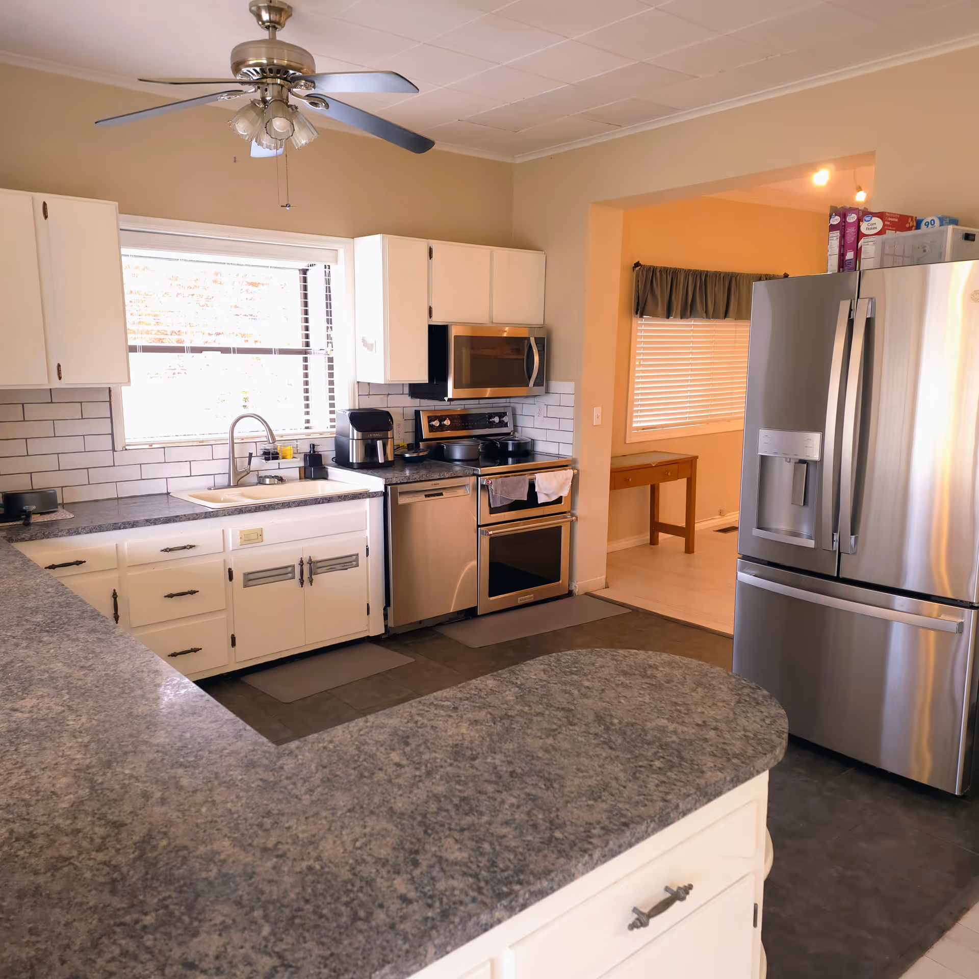 Bright kitchen with white cabinets, stainless steel appliances, and granite countertops.