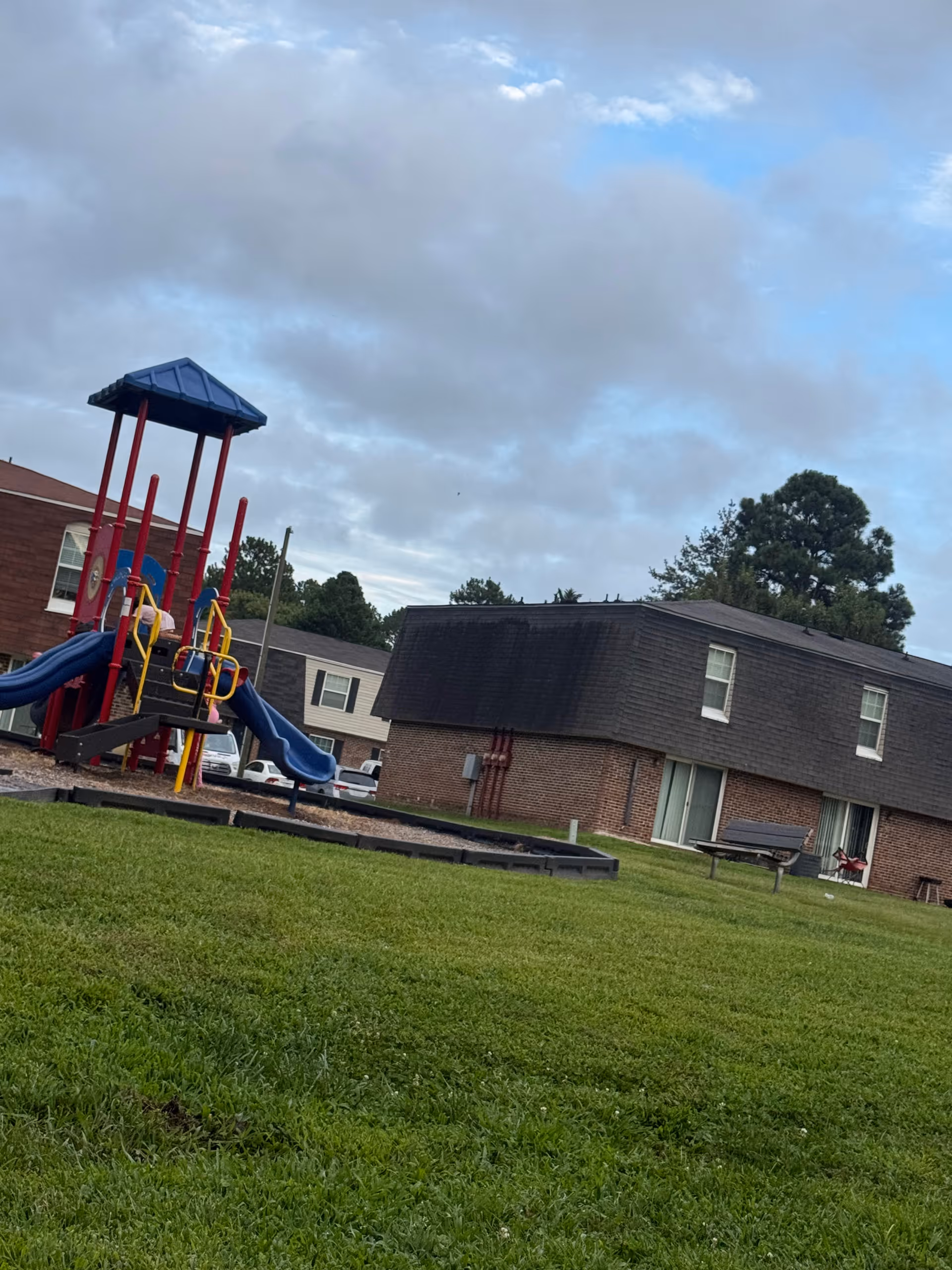 Outdoor playground with colorful equipment beside a brick senior living building.