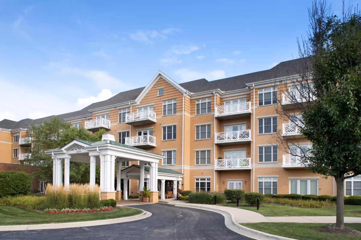 Brick senior living building with a covered entrance and landscaped circular driveway.