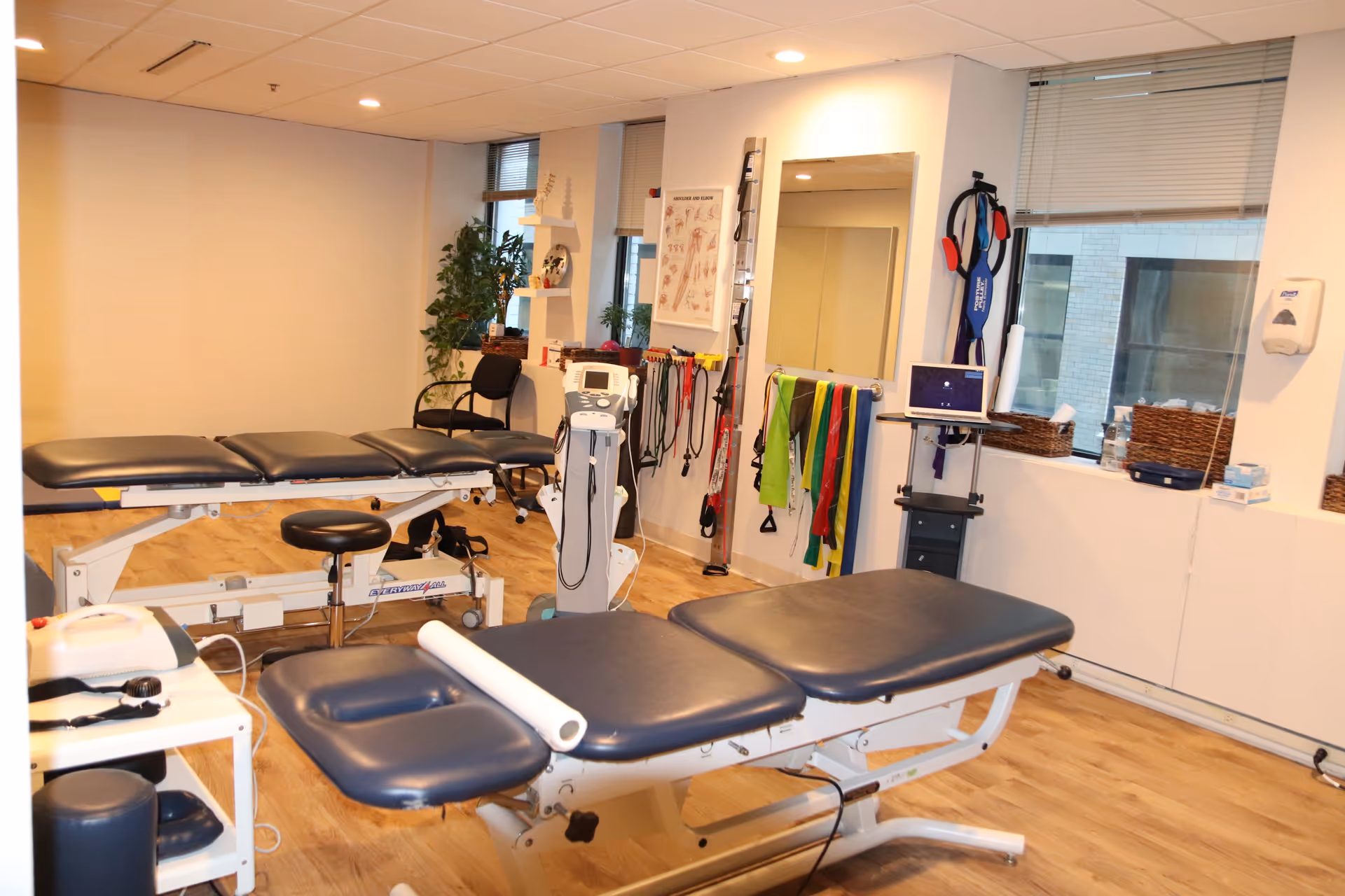 Physical therapy treatment room with adjustable tables, exercise equipment, and therapy accessories.