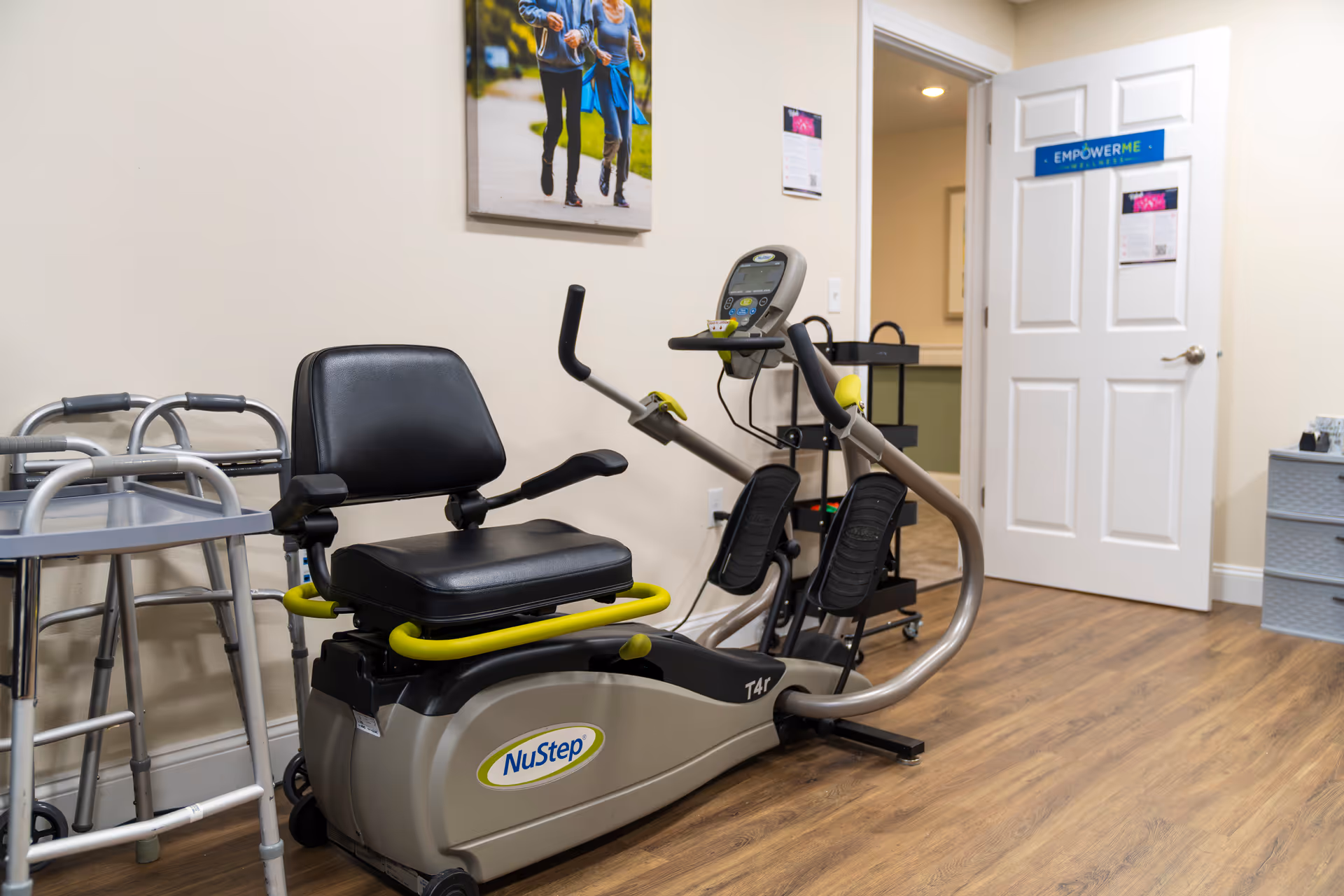 NuStep recumbent exercise machine in a small indoor fitness room with a walker nearby.