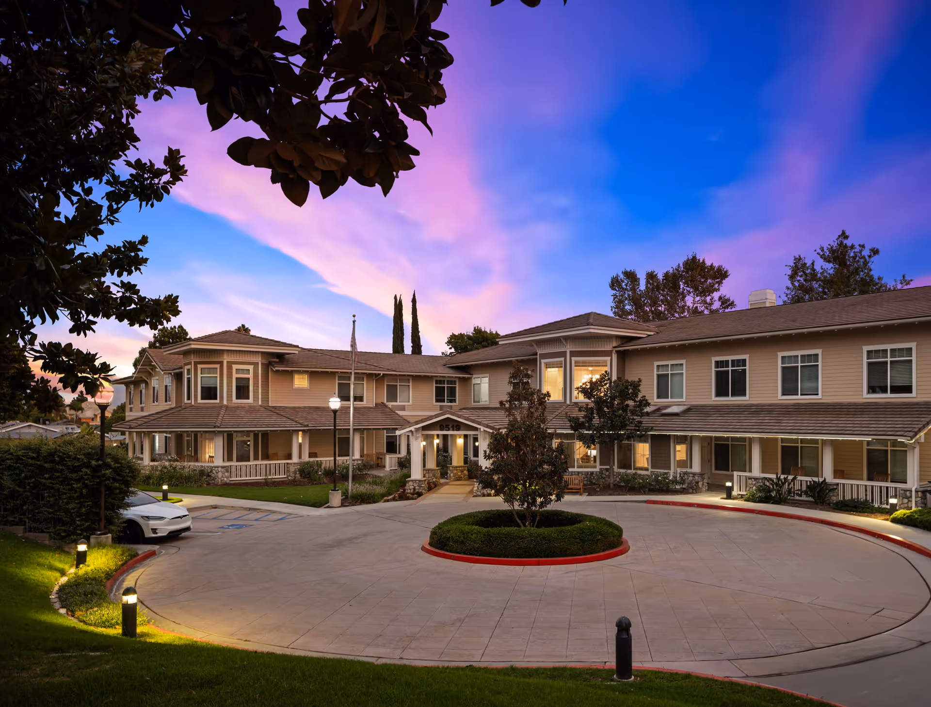 Exterior view of Ivy Park at Alta Loma, senior living campus with circular driveway at sunset.